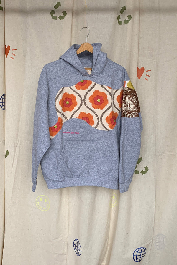 grey hoodie with colourful motif on front, sleeve and back. this upcycled gem is one of a kind and uses drapery samples to elevate this hoodie, repurposed in caanda