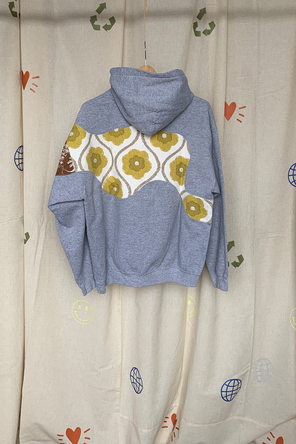 grey hoodie with colourful motif on front, sleeve and back. this upcycled gem is one of a kind and uses drapery samples to elevate this hoodie, repurposed in caanda