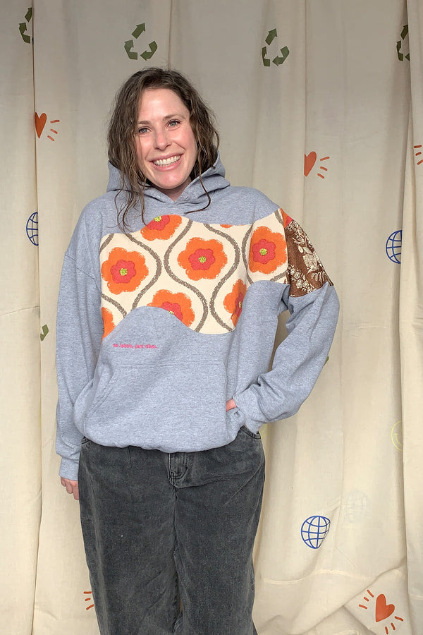 grey hoodie with colourful motif on front, sleeve and back. this upcycled gem is one of a kind and uses drapery samples to elevate this hoodie, repurposed in caanda