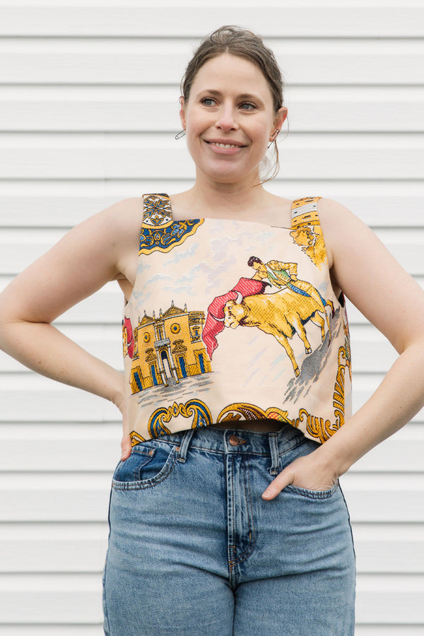 Woman wearing a colorful sleeveless top with graphic designs against a white background, matador and spanish print, upcycled in canada