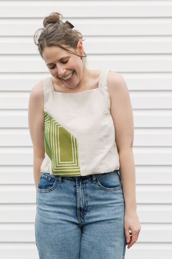 Woman wearing a sleeveless top with geometric design and jeans against a white background, cream and green tank top, upcycled in canada