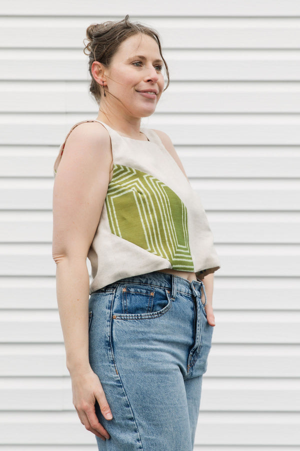 Woman wearing a sleeveless top with geometric design and jeans against a white background, cream and green tank top, upcycled in canada