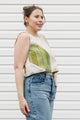Woman wearing a sleeveless top with geometric design and jeans against a white background, cream and green tank top, upcycled in canada