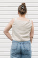 Woman wearing a sleeveless top with geometric design and jeans against a white background, cream and green tank top, upcycled in canada