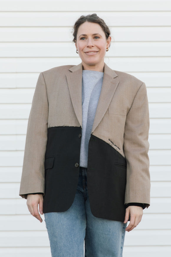 Person wearing a two-tone blazer with beige and black sections against a white background