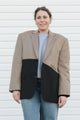 Person wearing a two-tone blazer with beige and black sections against a white background