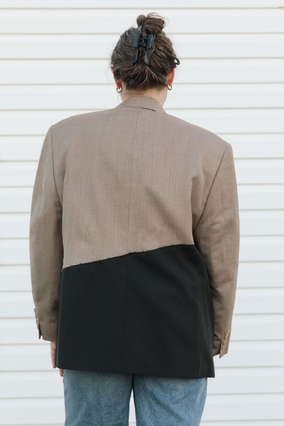 Person wearing a two-tone jacket with beige and black sections against a white background