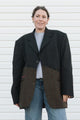Person wearing a black and brown coat against a white background