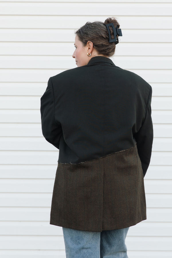 Person wearing a black and brown coat against a white background