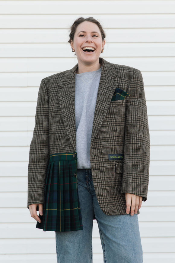 Person wearing a plaid blazer over a tartan skirt against a white background