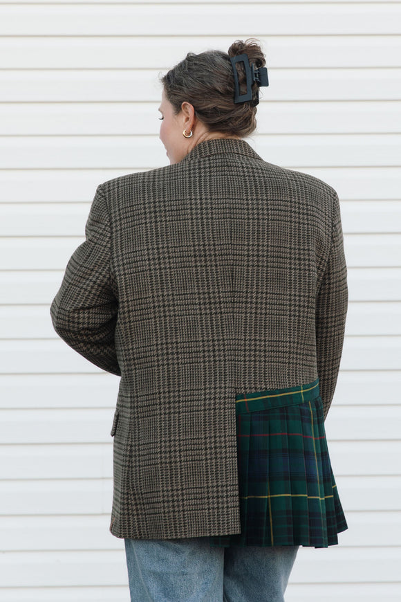 Person wearing a checkered blazer over a plaid skirt against a white background