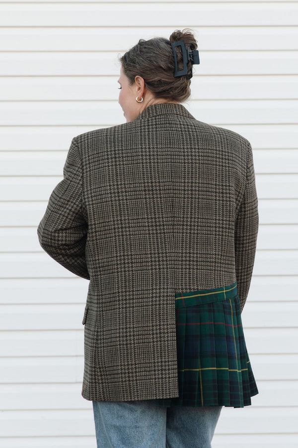Person wearing a checkered blazer over a plaid skirt against a white background