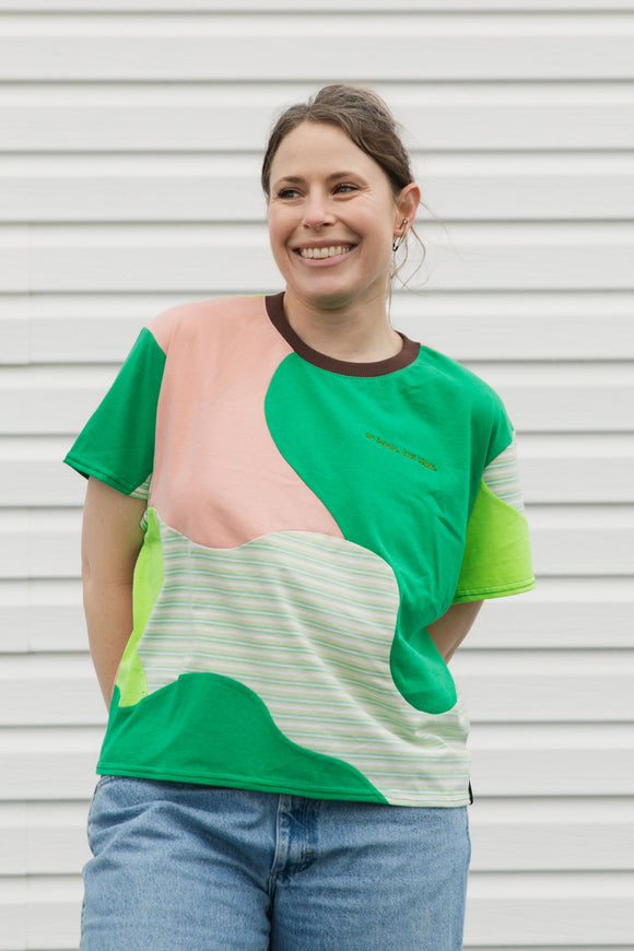Woman wearing a colorful shirt with green, pink, and striped patterns against a white background