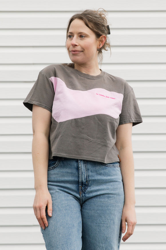 Person wearing a gray t-shirt with a pink design against a white background