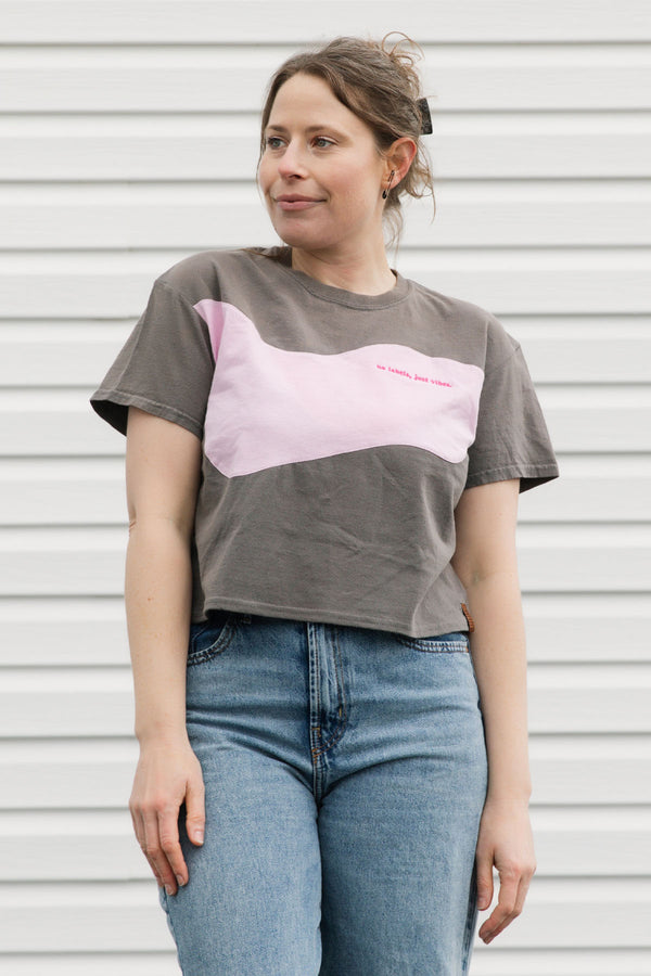 Person wearing a gray t-shirt with a pink design against a white background