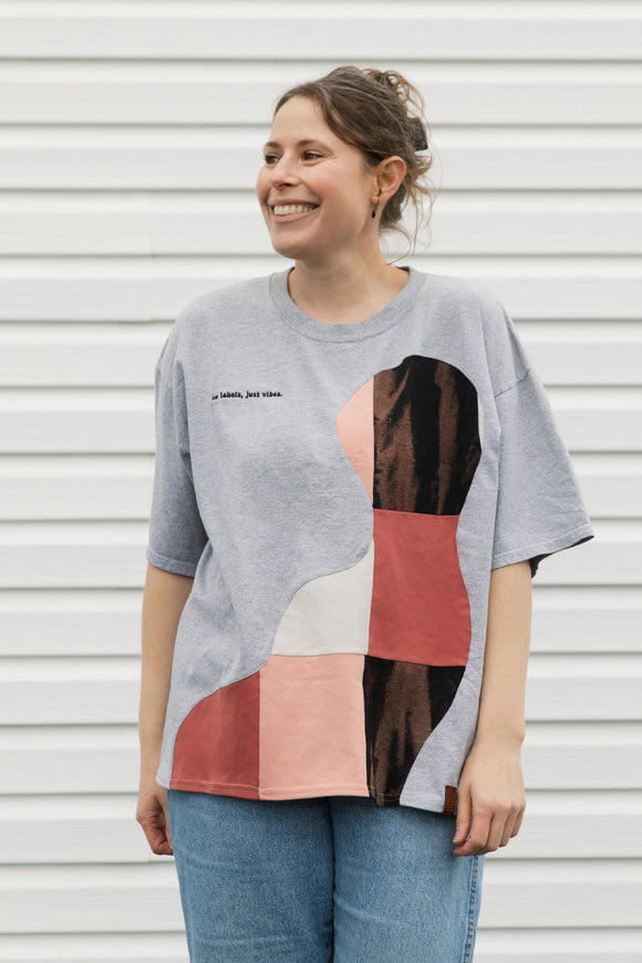 Woman wearing a gray t-shirt with a colorful abstract design against a white background