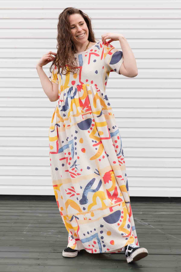 maxi dress with sleeve, pockets and a slight empire waist. dress has abstract colourful print. made in canada