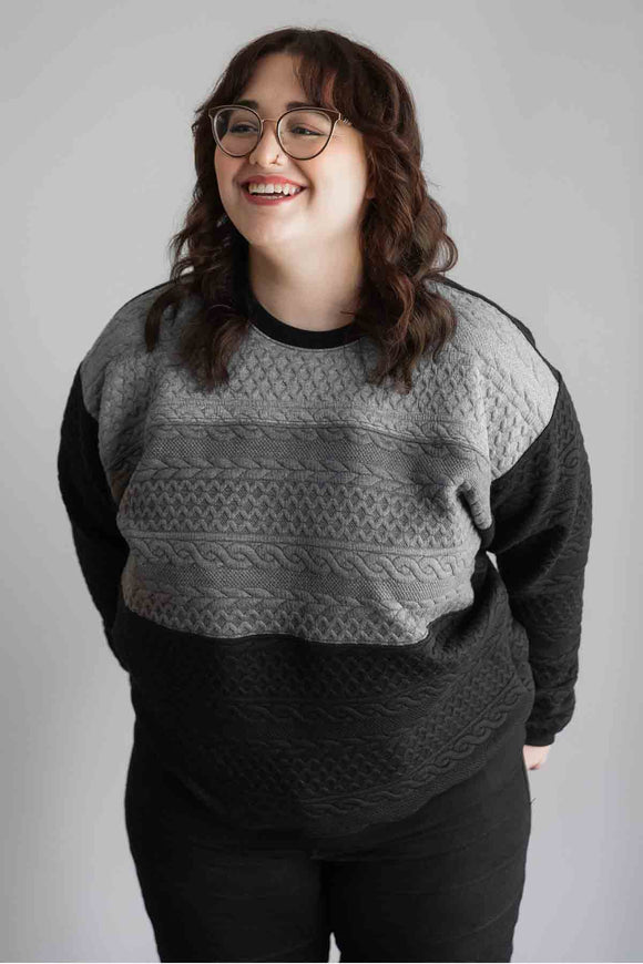 woman wearing oversized, comfy sweater with ombre grey to black design, handmade in Ottawa, cable knit design detail