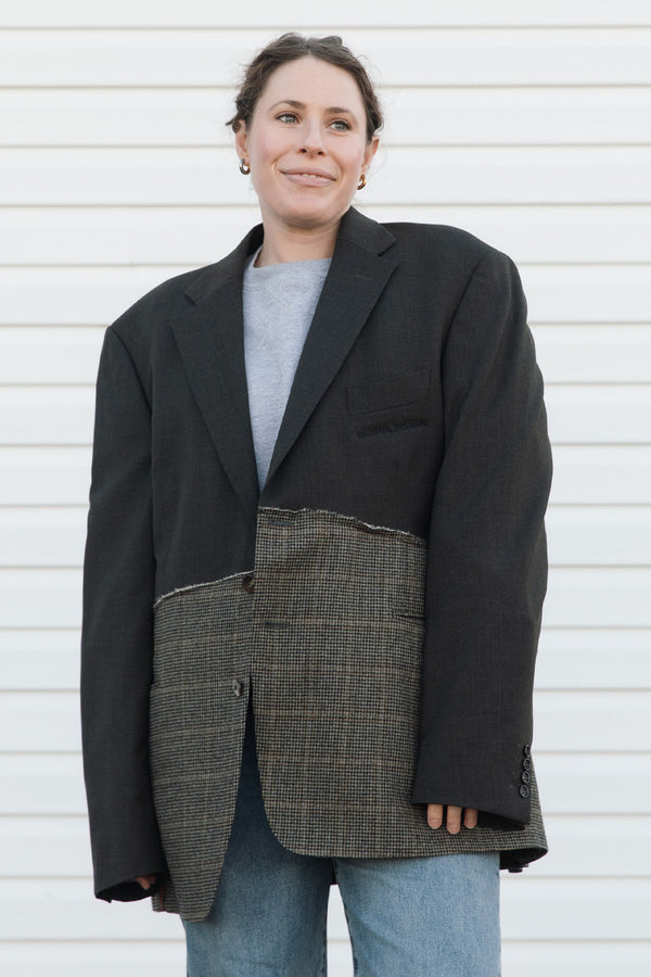Person wearing a black and plaid blazer against a white background
