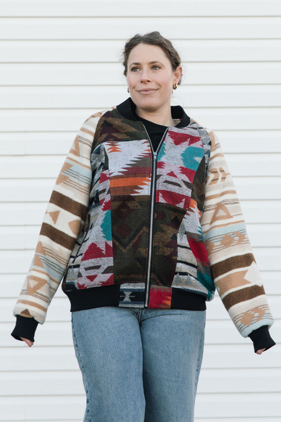 Person wearing a colorful patterned jacket against a white wall