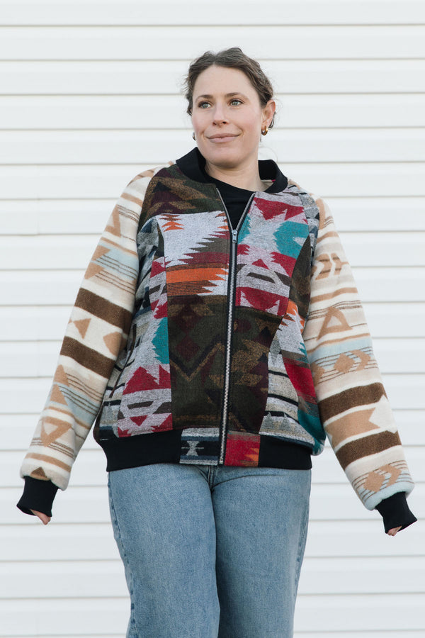 Person wearing a colorful patterned jacket against a white wall