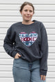 Person wearing a dark gray sweatshirt with a colorful heart design sewn in canada