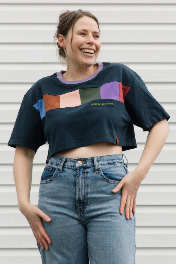 Person wearing a colorful graphic t-shirt and blue jeans against a plain background
