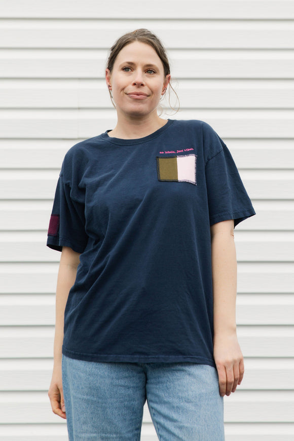 Woman wearing a navy blue t-shirt with a colorful patch on a white background