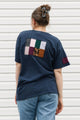 Person wearing a navy blue t-shirt with a colorful patch on the back against a white background