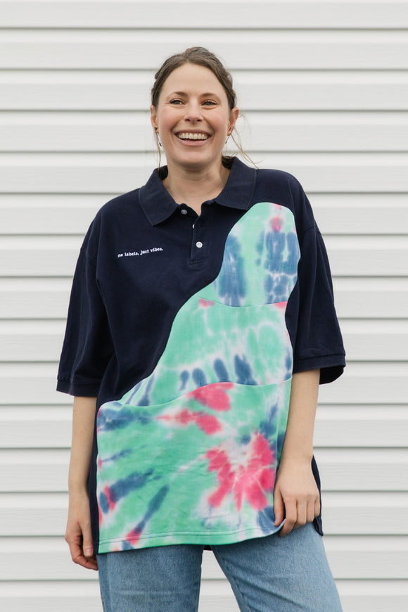 Person wearing a navy polo shirt with a tie-dye design, standing against a plain background.