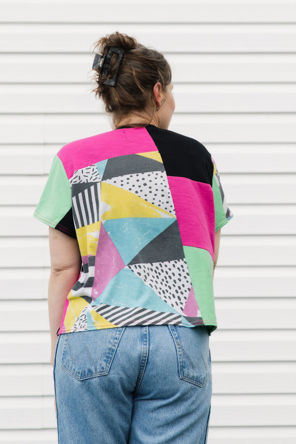 Person wearing a colorful geometric-patterned shirt with a plain background