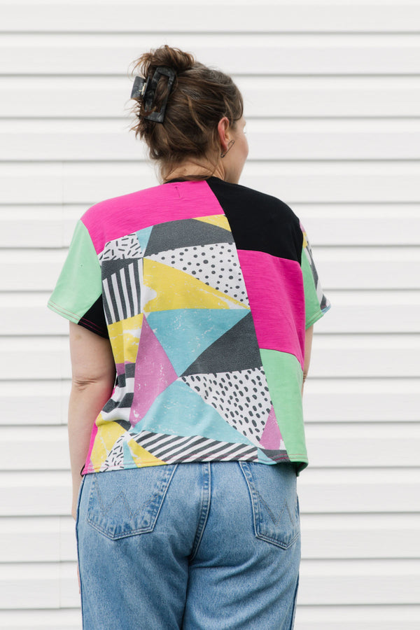 Person wearing a colorful geometric-patterned shirt with a plain background