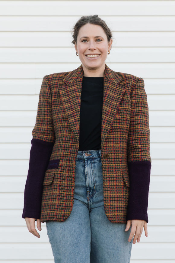 Person wearing a plaid blazer with purple sleeves against a white background