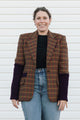 Person wearing a plaid blazer with purple sleeves against a white background