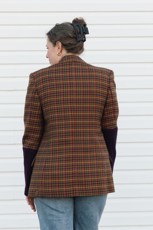 Person wearing a plaid jacket against a white wall