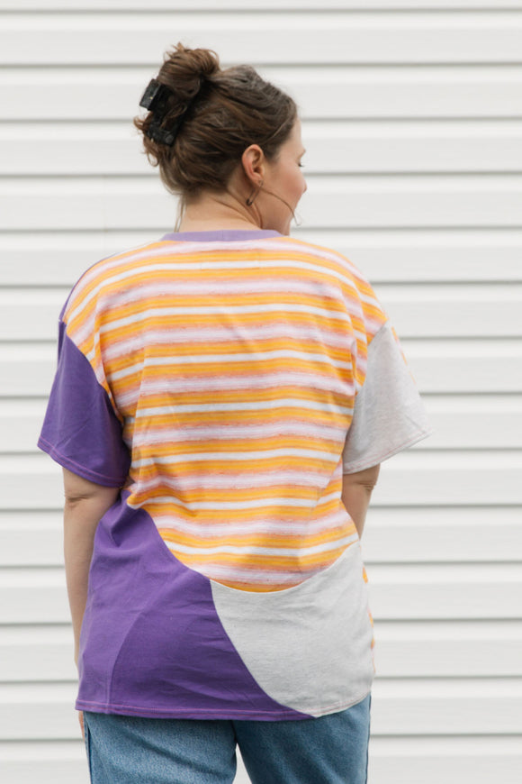 Person wearing a colorful striped shirt against a white wall