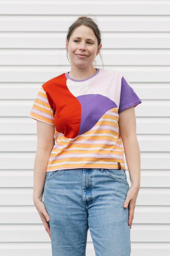 Woman wearing a colorful geometric-patterned shirt against a white background