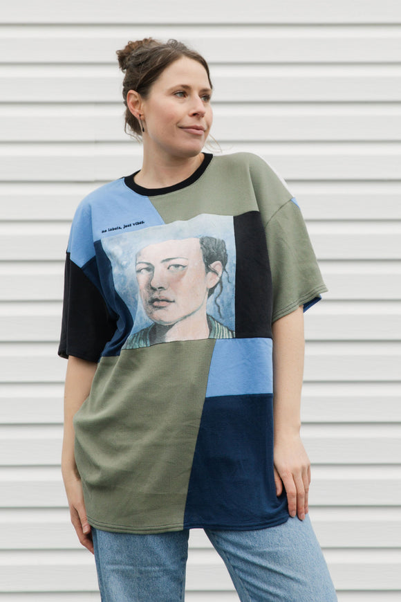 Woman wearing a patchwork-style t-shirt with a graphic design against a plain background