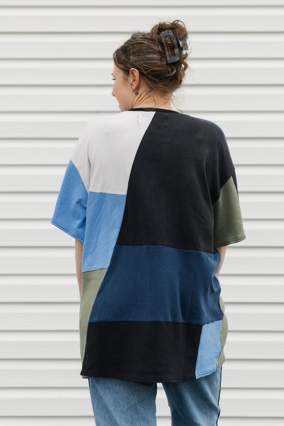 Person wearing a color-blocked sweater in front of a white wall