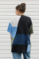 Person wearing a color-blocked sweater in front of a white wall