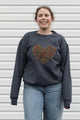 Woman wearing a dark gray sweatshirt with a colorful heart design sewn in canada