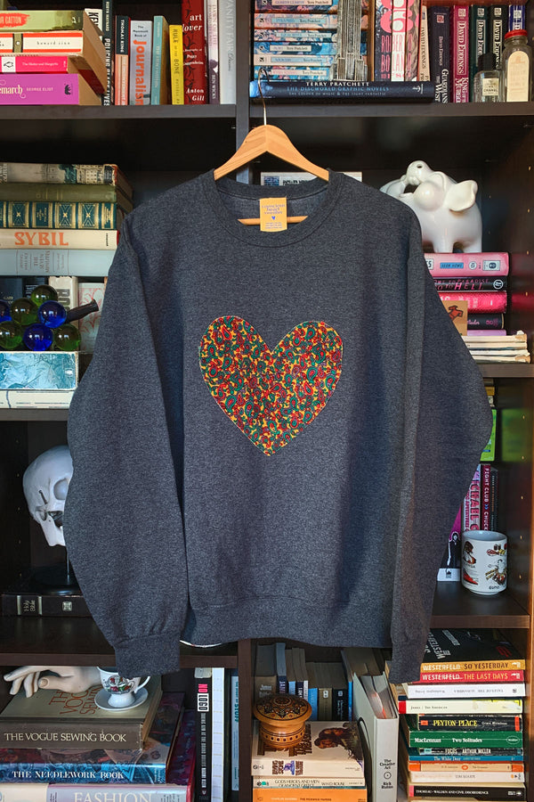 Woman wearing a dark gray sweatshirt with a colorful heart design sewn in canada