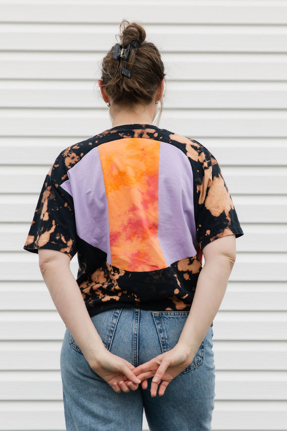Person wearing a tie-dye shirt with purple and orange details, upcycled in canada