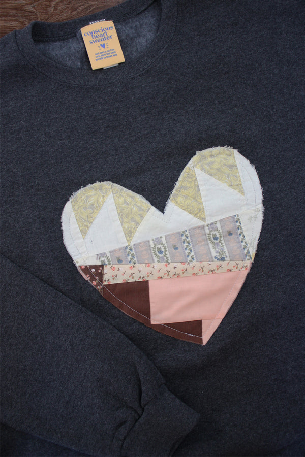 Dark Grey sweatshirt with a patchwork heart design on a wooden surface