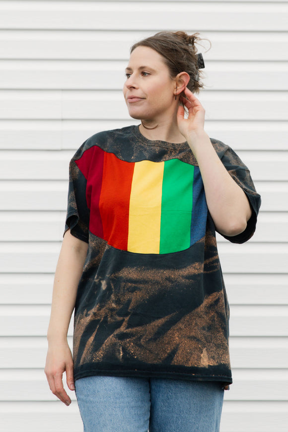 Woman wearing a colourful shirt with a rainbow across the front, upcycled in canada