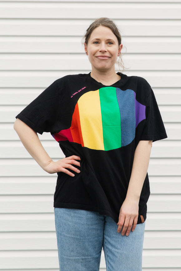 Person wearing a black t-shirt with a rainbow design in front of a white background