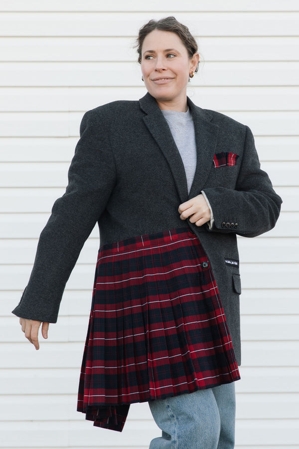 Woman wearing a gray coat with a red plaid skirt against a white background