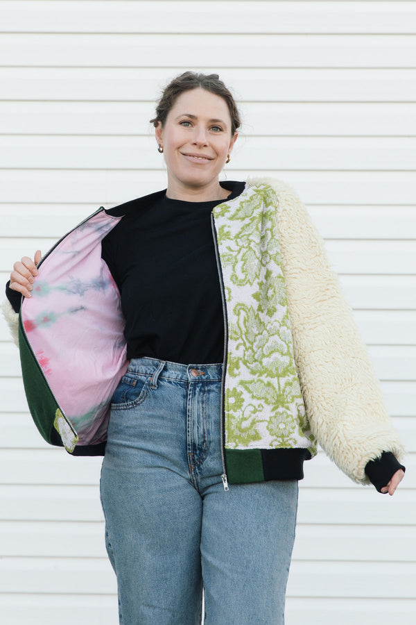 Person wearing a green and white patterned jacket with shaggy sleeves, upcycled in canada