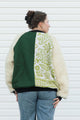 Person wearing a green and white patterned jacket with shaggy sleeves, upcycled in canada
