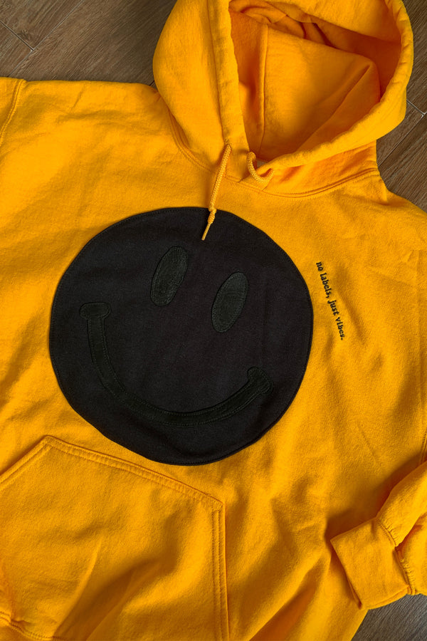 yellow hoodie with black smiley face on the front, repurposed and upcycled in canada